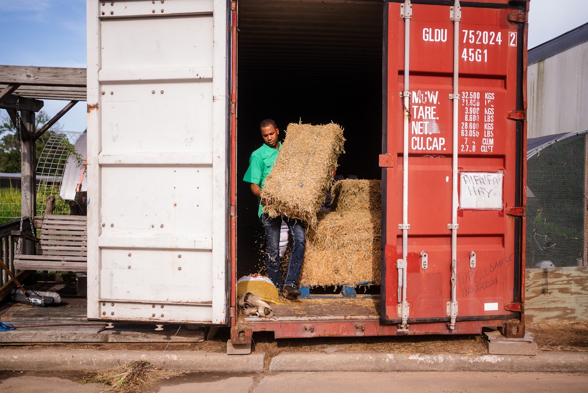 A farm worker loading hay bales for delivery
